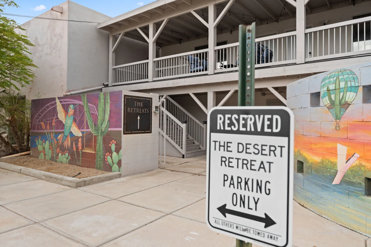 Reserved parking sign reading The Desert Retreat Parking Only, with the stairs and The Retreats sign behind it