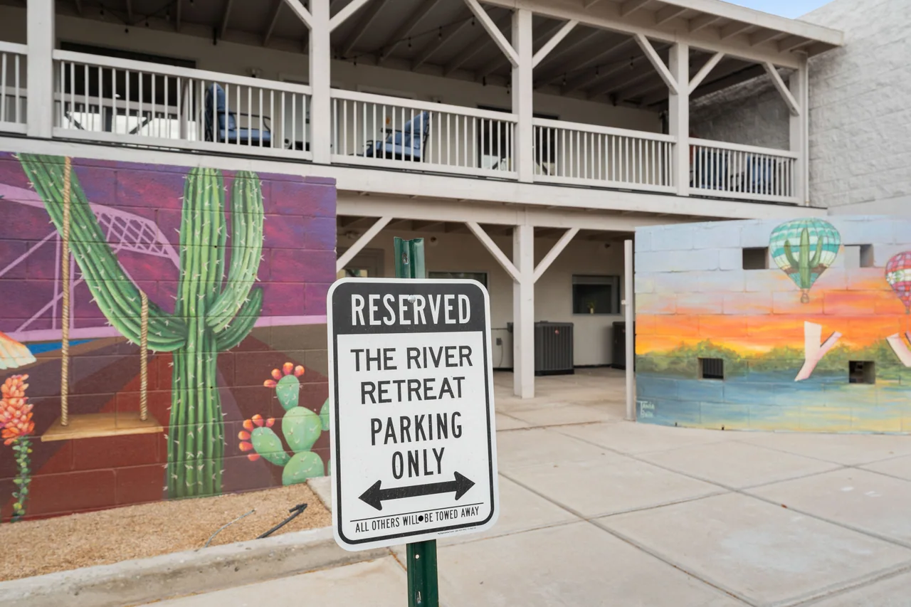 Reserved parking sign reading The River Retreat Parking Only, in front of the cactus mural